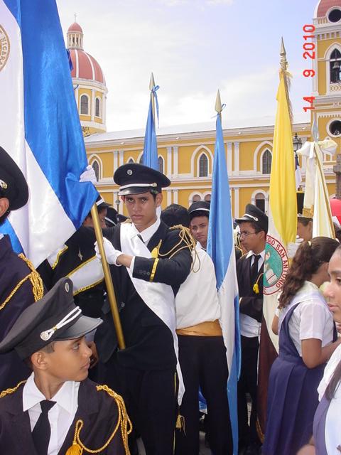 El joven Stirle Munoz, luciendo su pulcro uniforme negro con kepis y charrateras, rsguarda la gloriosa bandera azul y blanco.